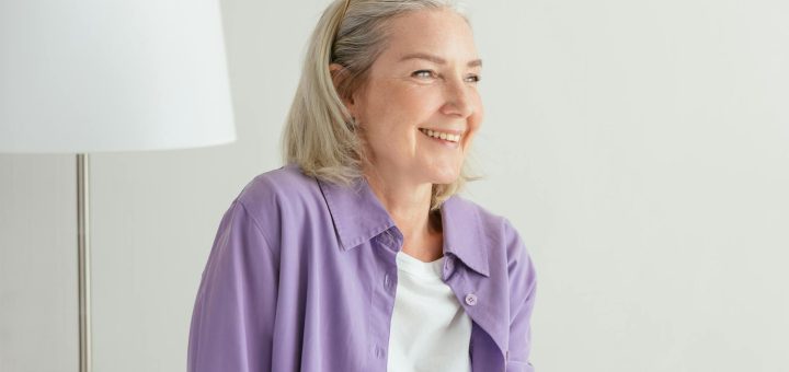 an elderly woman in purple long sleeves smiling