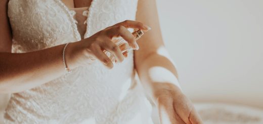 unrecognizable woman in white lacy dress spraying perfume on wrist