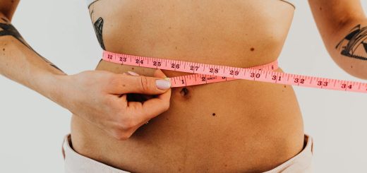woman measuring waistline with a pink tape measure
