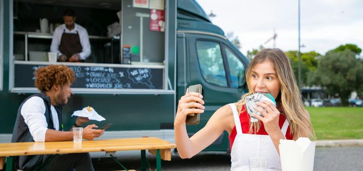 happy female eating hamburger and taking selfie