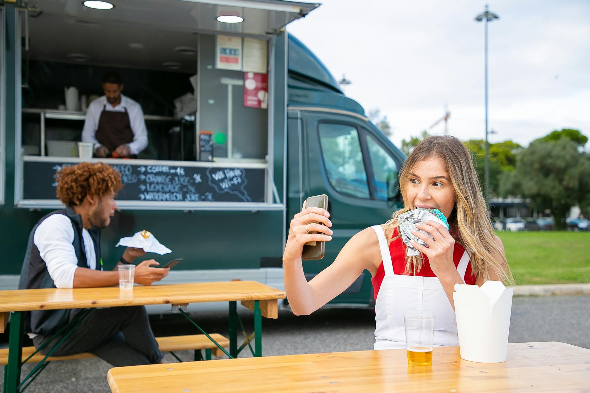 happy female eating hamburger and taking selfie