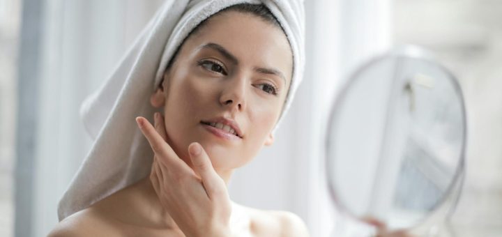 selective focus portrait photo of woman with a towel on head looking in the mirror