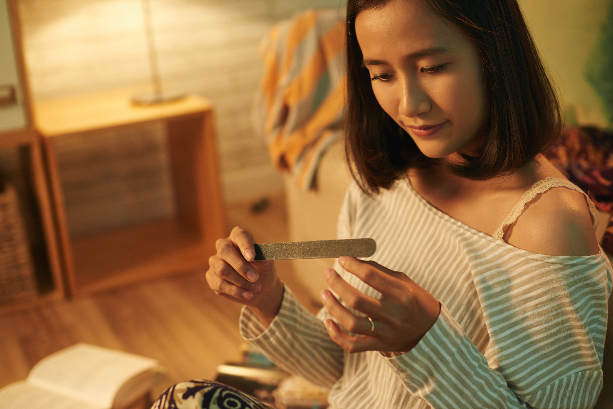 Lovely Asian woman filing nails in the evening