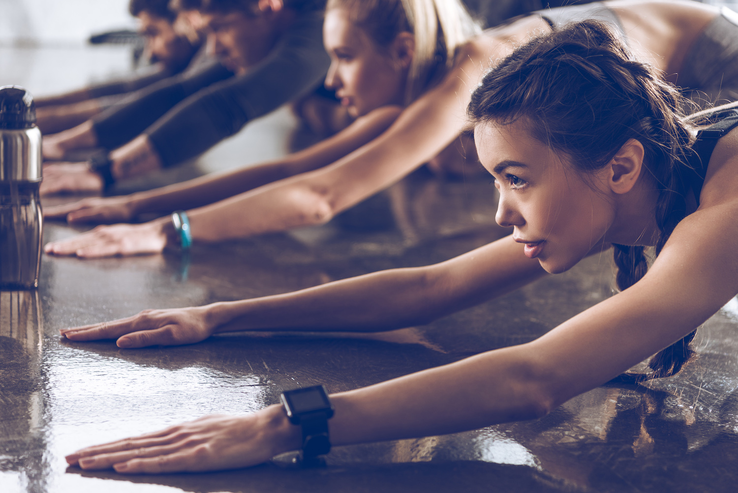 group of athletic young people in sportswear stretching at the gym, group fitness concept