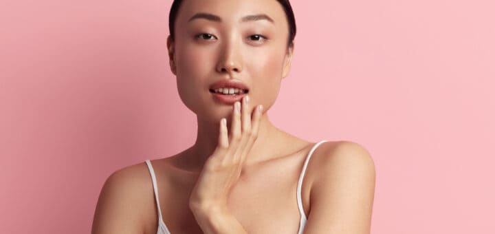 Tender Woman Touching Lips. Portrait of Asian Woman Touching her Face and Smiling. Woman Appearance and Skin Care Concept