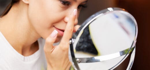 Young woman putting contact lens in her eye, close up.